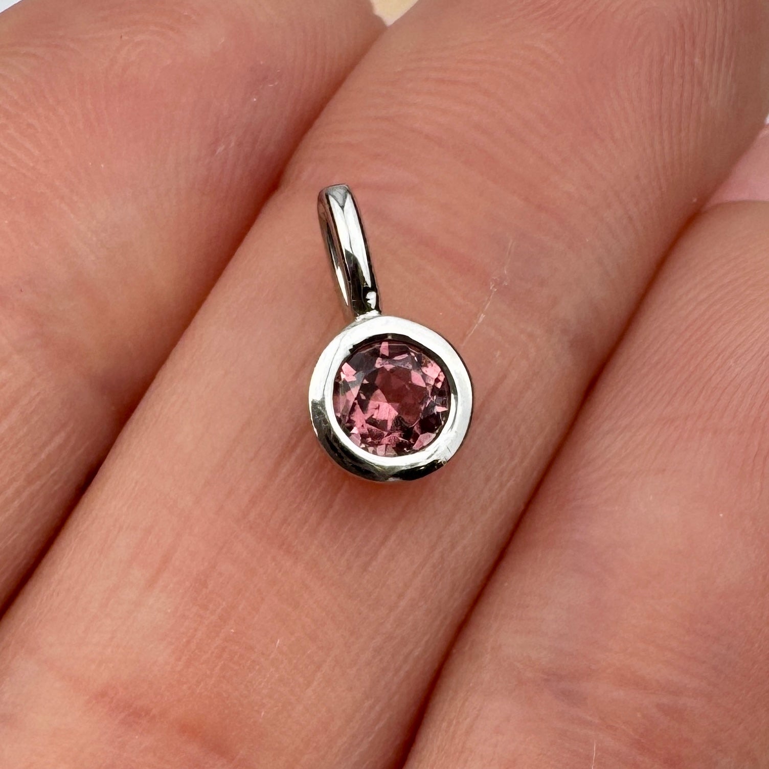 round pink gemstone pendant set in a silver bezel