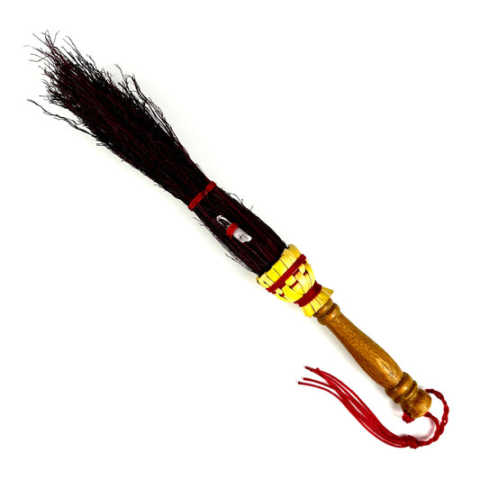 traditional broom with a wooden handle and red bristles
