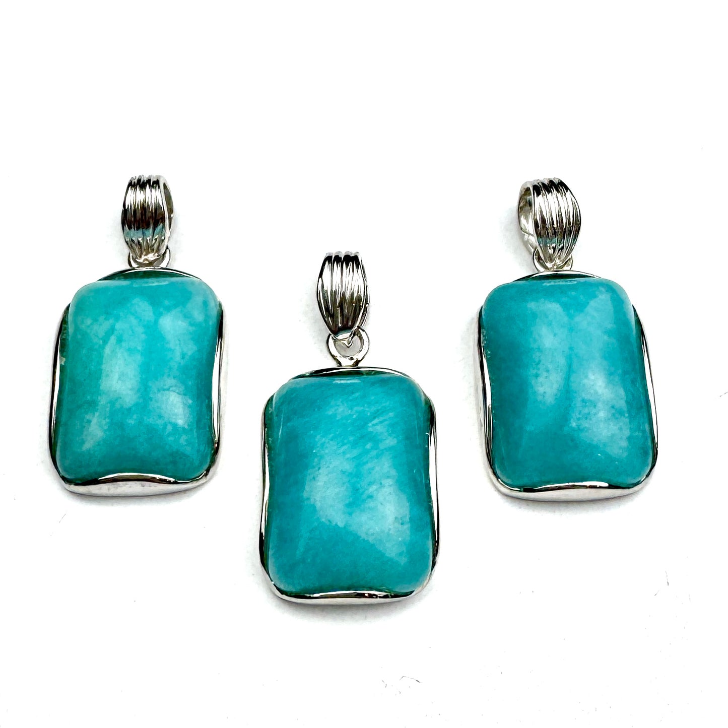 three turquoise gemstone pendants with silver settings