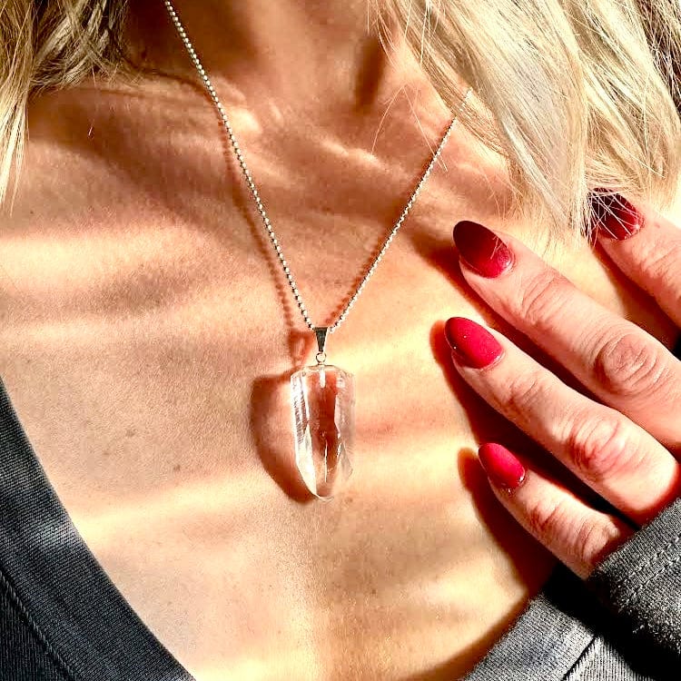 close-up of a person wearing a clear crystal pendant necklace