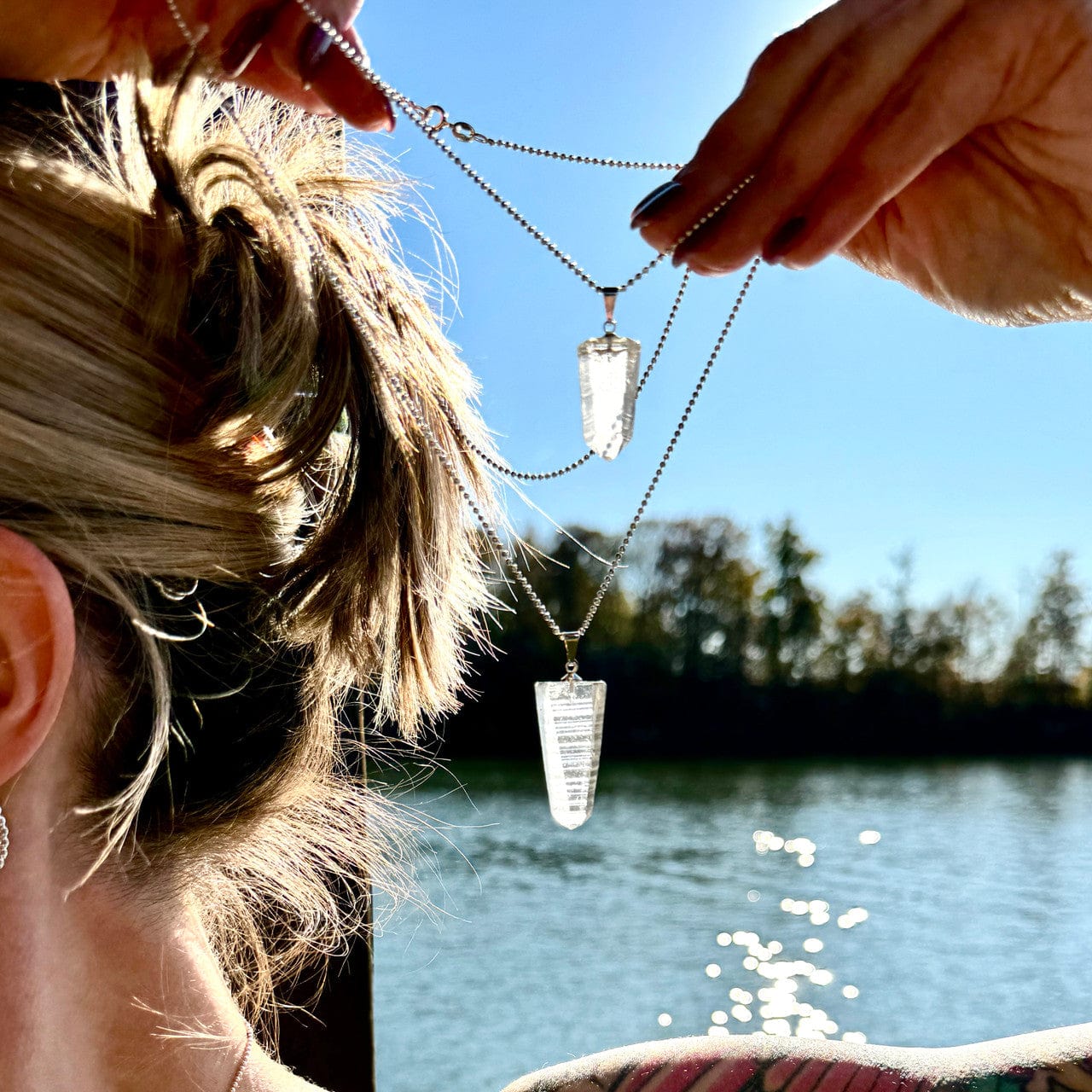 person holding two clear crystal pendants